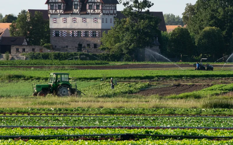 Blick auf das Schloss Neunhof mit Feldarbeitern im Vordergrund